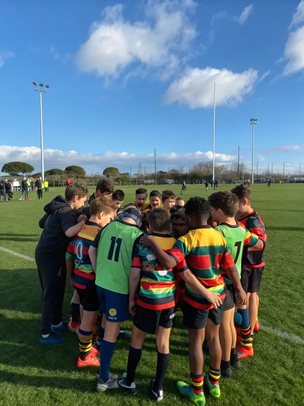A vibrant image of young children participating in a rugby training session, showcasing the fun and inclusive nature of the program. The children are laughing and actively engaged, with coaches providing guidance in the background. This image is for the 'Youth Rugby Clinics' program.